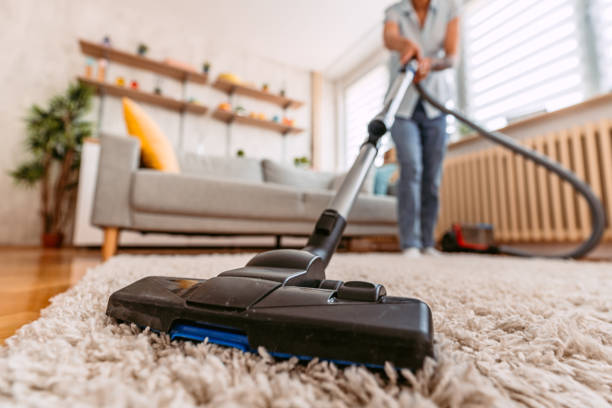 Beautiful senior woman vacuuming the carpet in her apartment.