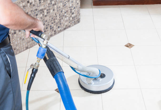 Man cleaning tile and grout with machine in bathroom