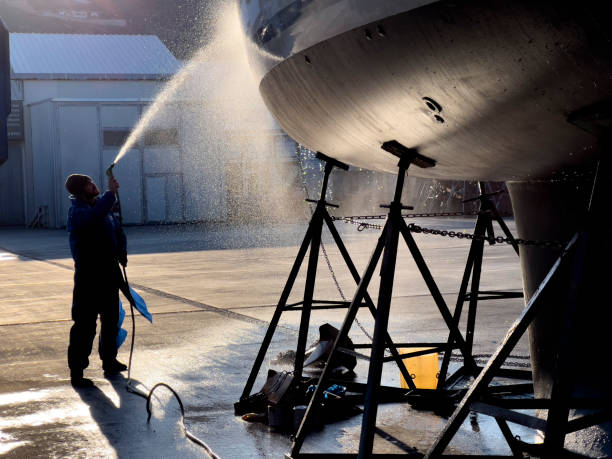 worker spraying water on the bottom of private boat