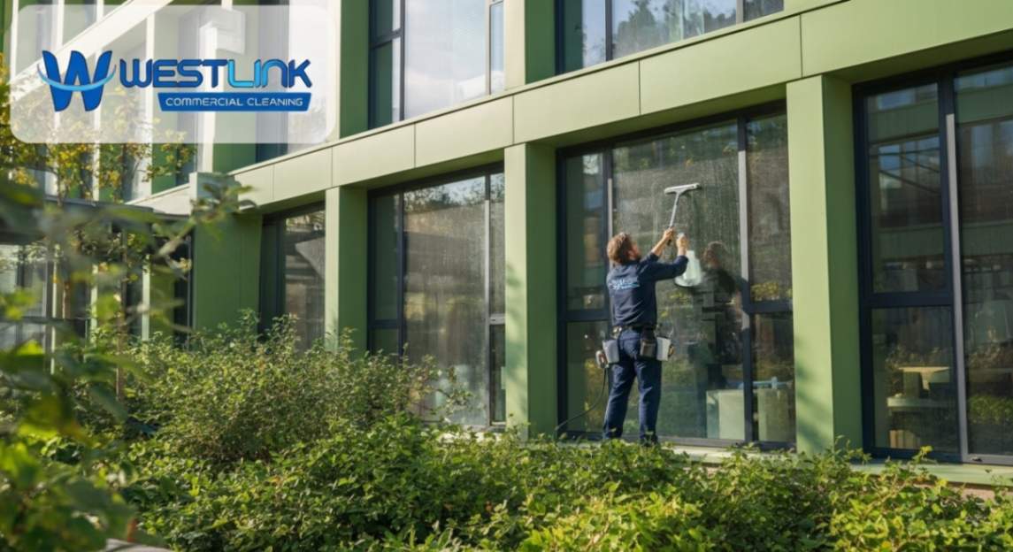 Professional commercial window cleaner working on a modern glazed building