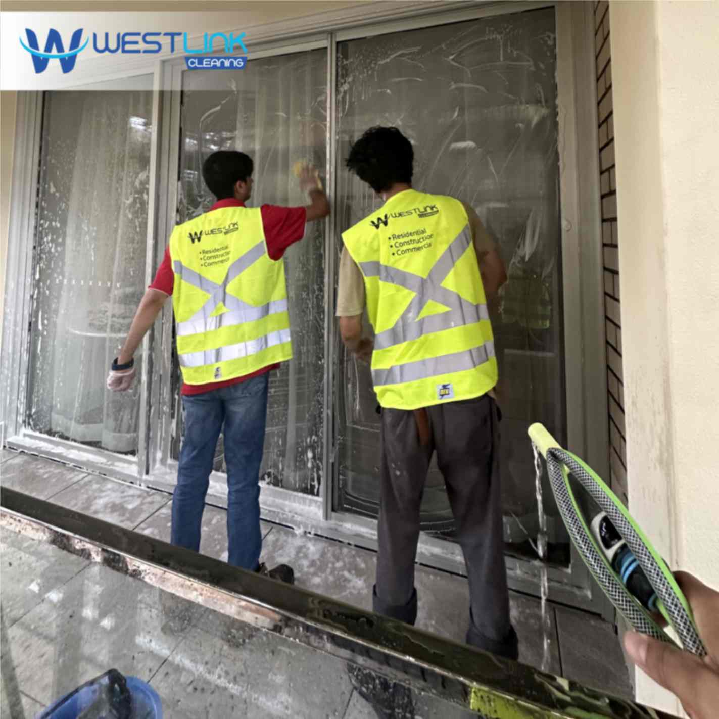 Cleaner wiping interior windows with a squeegee and microfiber cloth to remove dust and streaks from glass.
