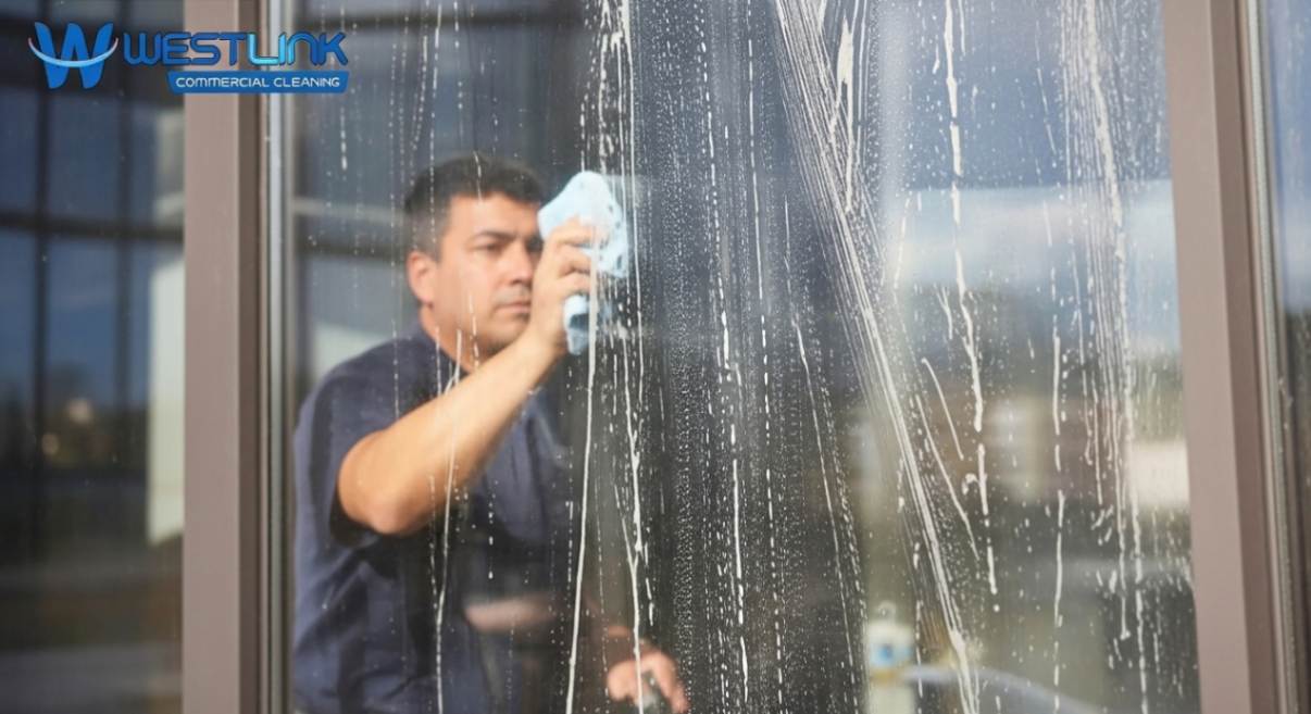 Professional cleaner making a common commercial window cleaning mistake by cleaning glass in direct sunlight, causing streaks.