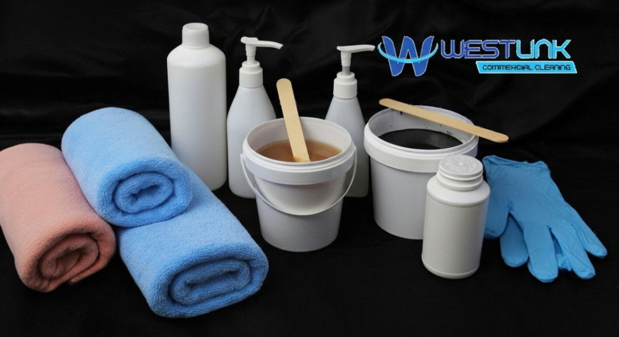 Assorted cleaning supplies including bottles, buckets, towels, and gloves on a black background.