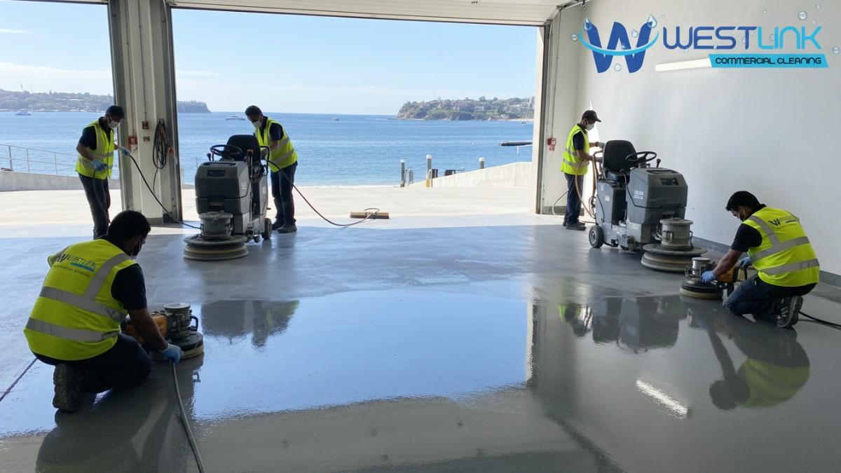 Workers polishing epoxy garage floor with machinery in a Manly waterfront home.
